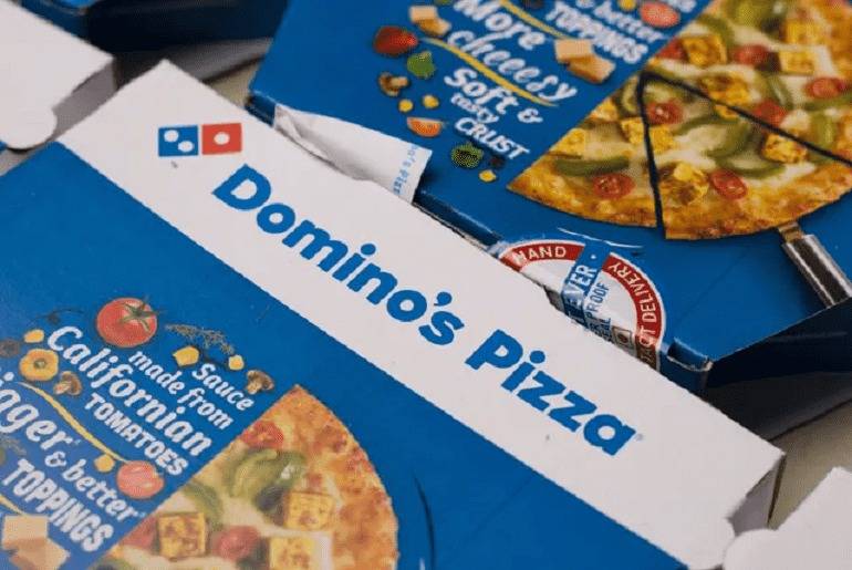 This picture depicts two pizza boxes with the branding of Domino’s Pizza