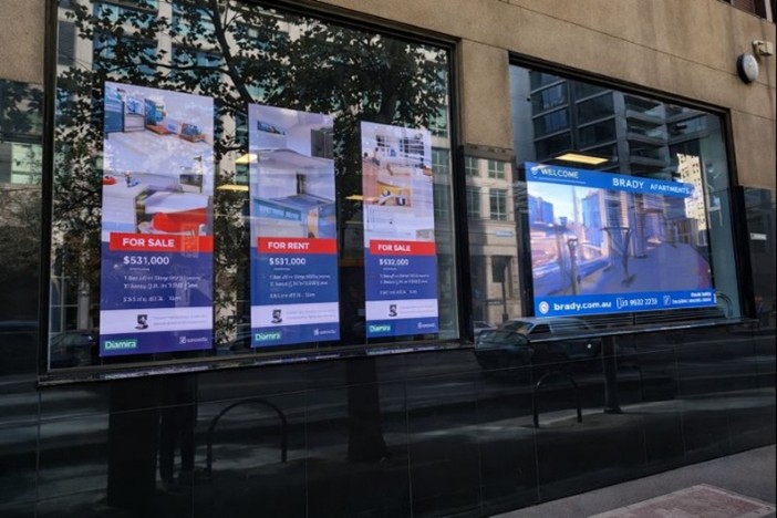Real estate property listings displayed on storefront glass windows
