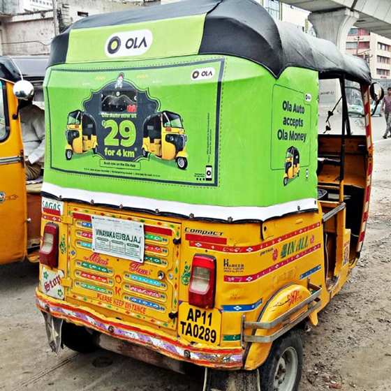 Auto Rickshaw Advertising Format Ola advertisement displayed on the back of an auto rickshaw in city traffic