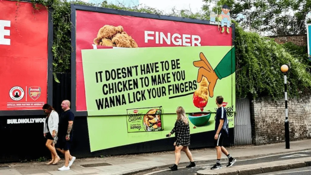 Creative Outdoor Billboard Advertising with Food Messaging Large roadside billboard with creative copy and fried chicken visuals designed to attract attention from pedestrians walking by.