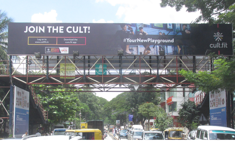 Cult.fit Flyover Billboard Outdoor Campaign Large billboard on a flyover promoting Cult.fit fitness app with traffic moving below in a busy urban setting.