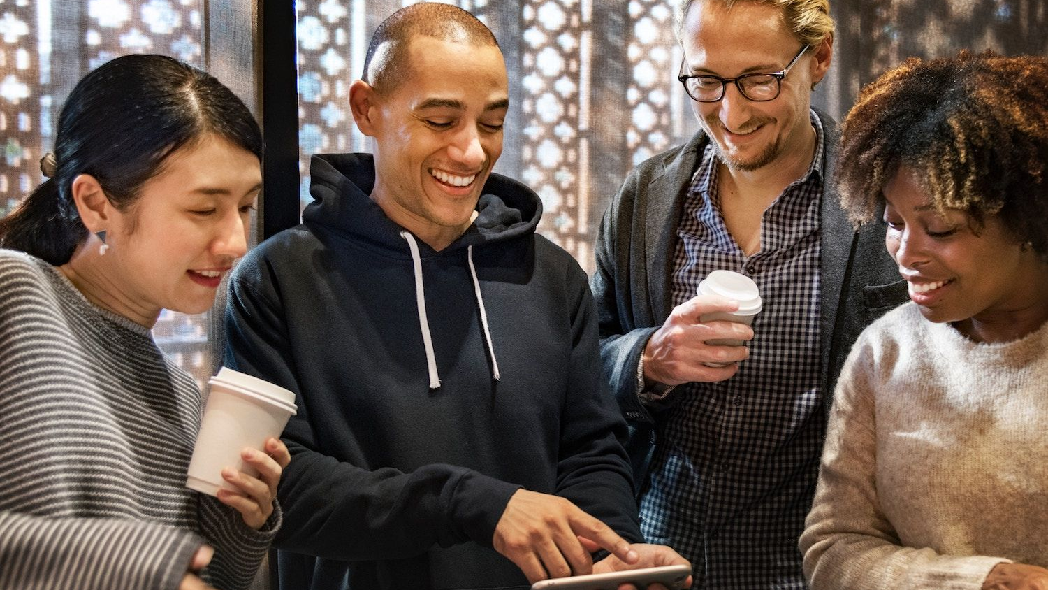 Social commerce and customer engagement for D2C brands Group of people using a smartphone together representing social commerce, word-of-mouth, and community-driven D2C marketing