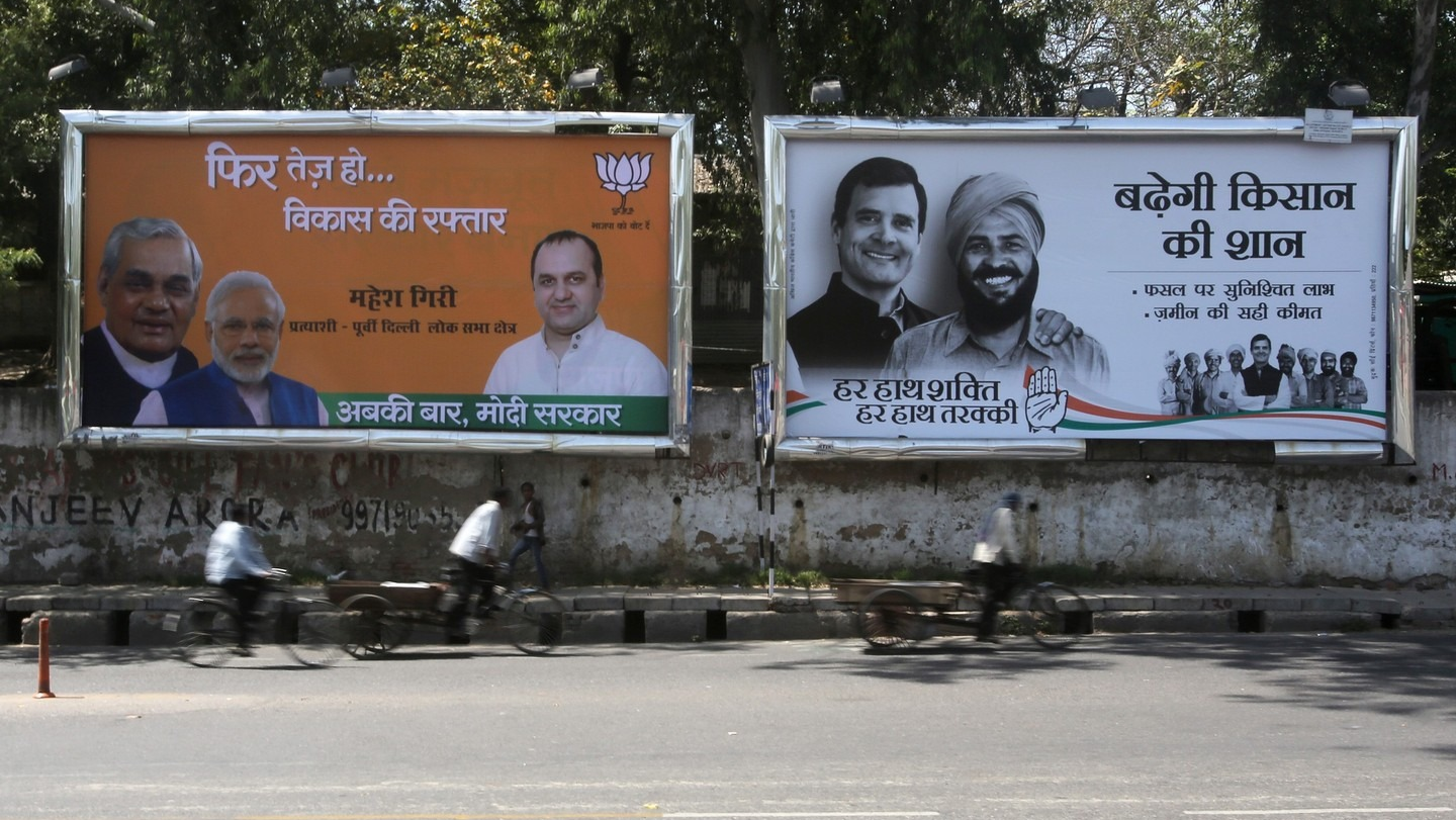 BJP vs Congress Election Campaign Billboards on Delhi Street | Indian General Elections BJP and Congress election campaign billboards in Hindi displayed side by side on a Delhi street, with cyclists passing in the foreground