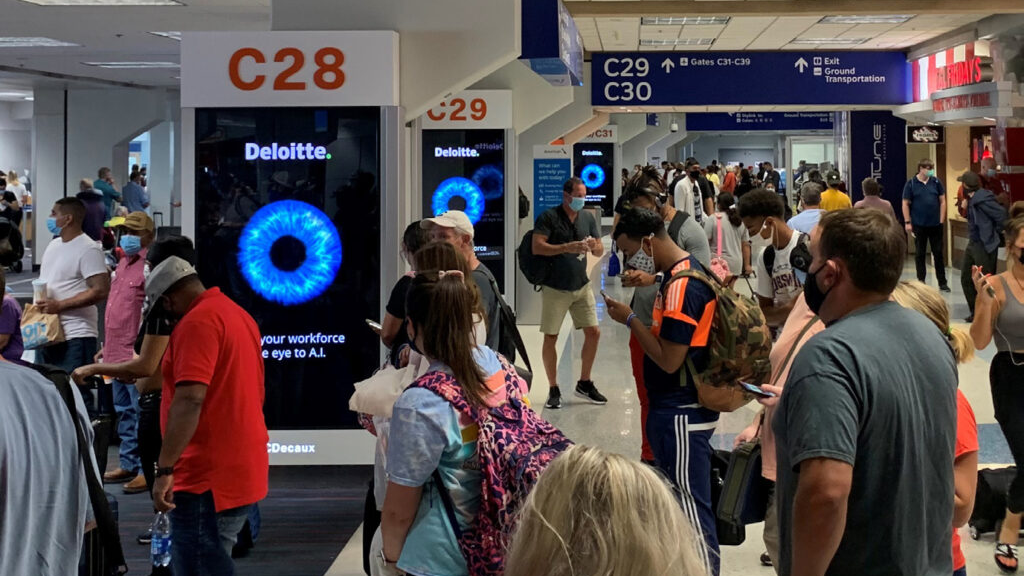 Airport Terminal Digital Advertising Displays Crowded airport terminal featuring vertical digital advertising displays promoting Deloitte branding between departure gates.