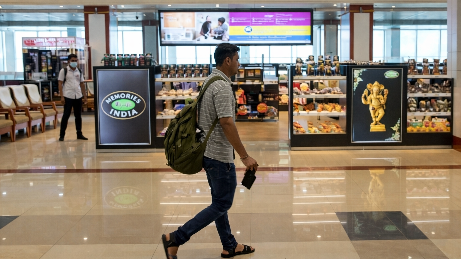 Retail Advertising Displays Inside Airport Shopping Area Airport retail area featuring illuminated digital displays for “Memories of India” gift store with passengers walking nearby.